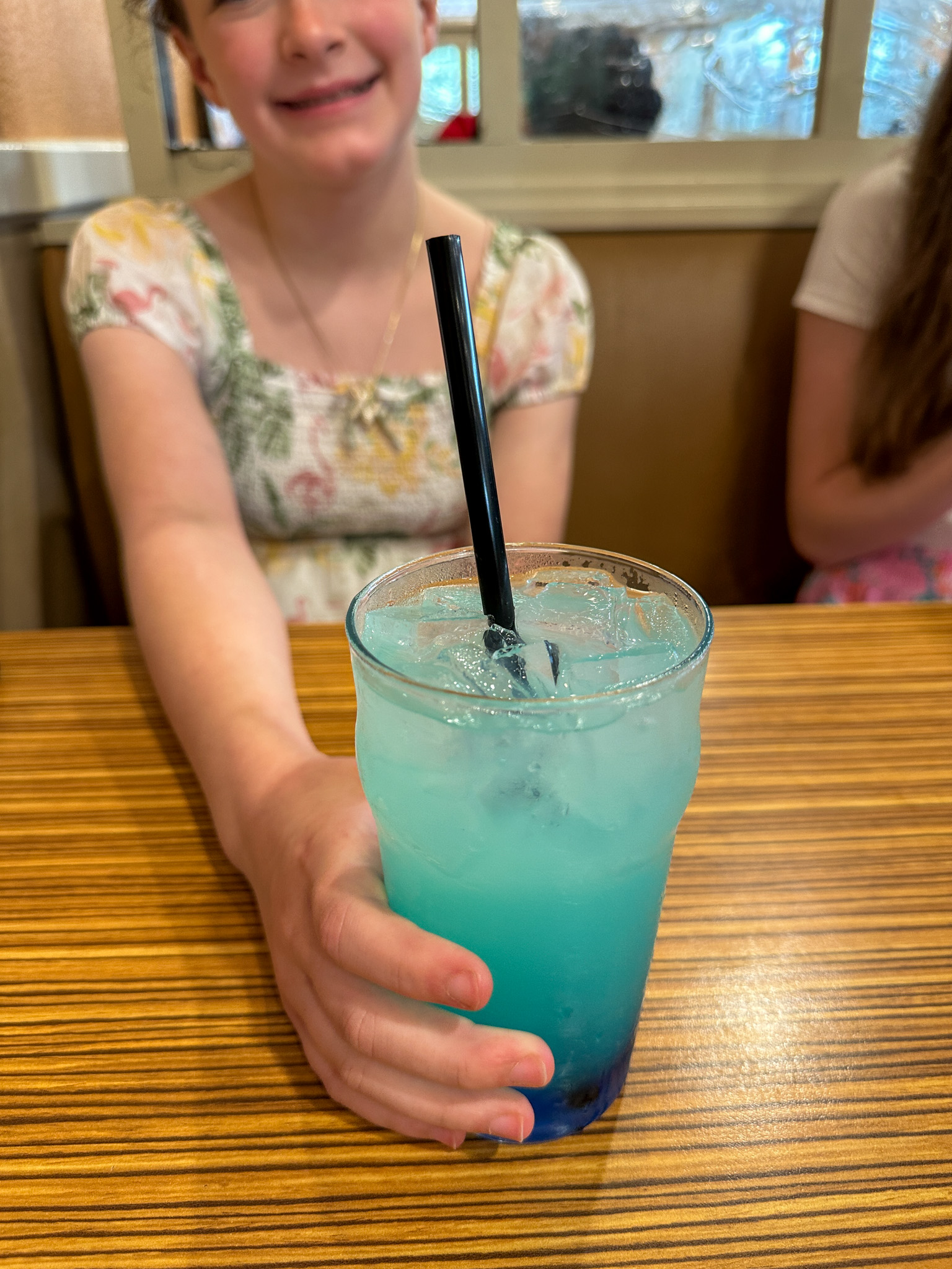 little girl holds blue drink for verb in English for taking drink orders