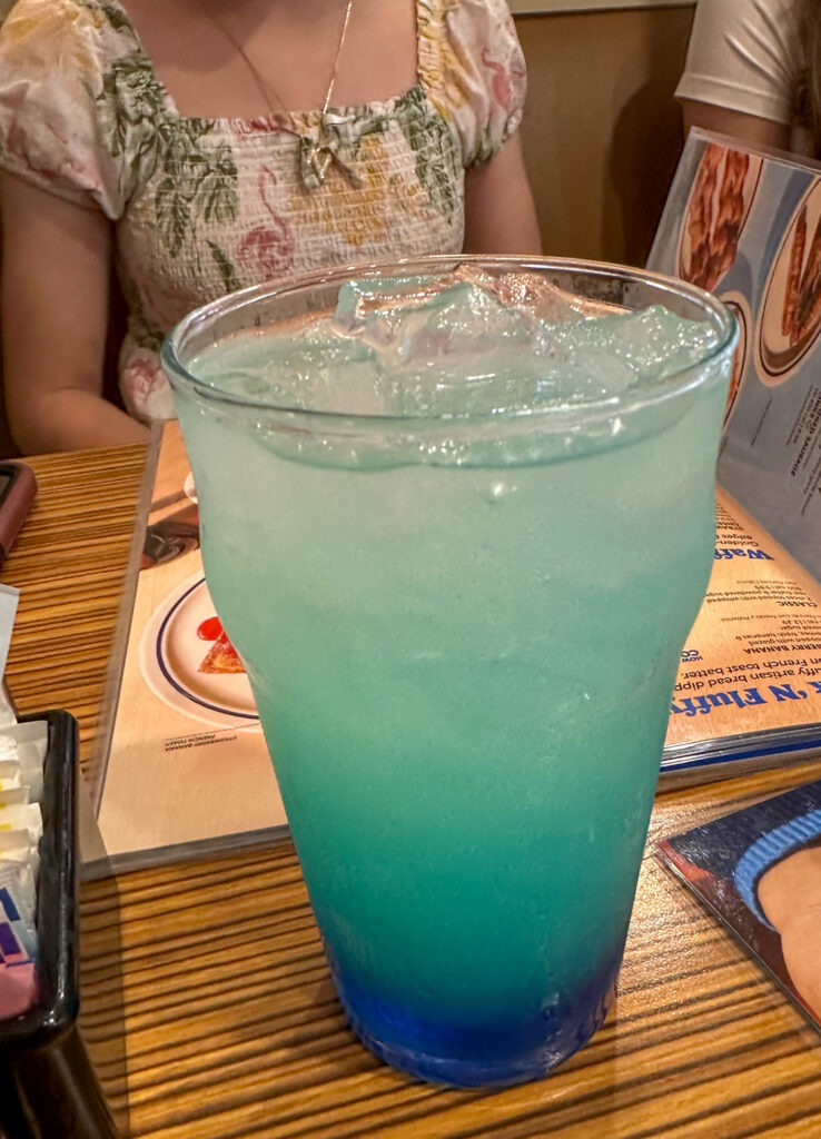 a blue lemonade drink in front of a young lady for how to take orders for drinks in English